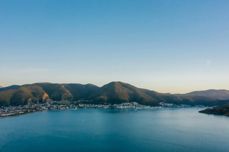 a large body of water surrounded by mountains, a tilt shift photo, by Lee Loughridge, pexels contest winner, picton blue, taken at golden hour, city views, thumbnail
