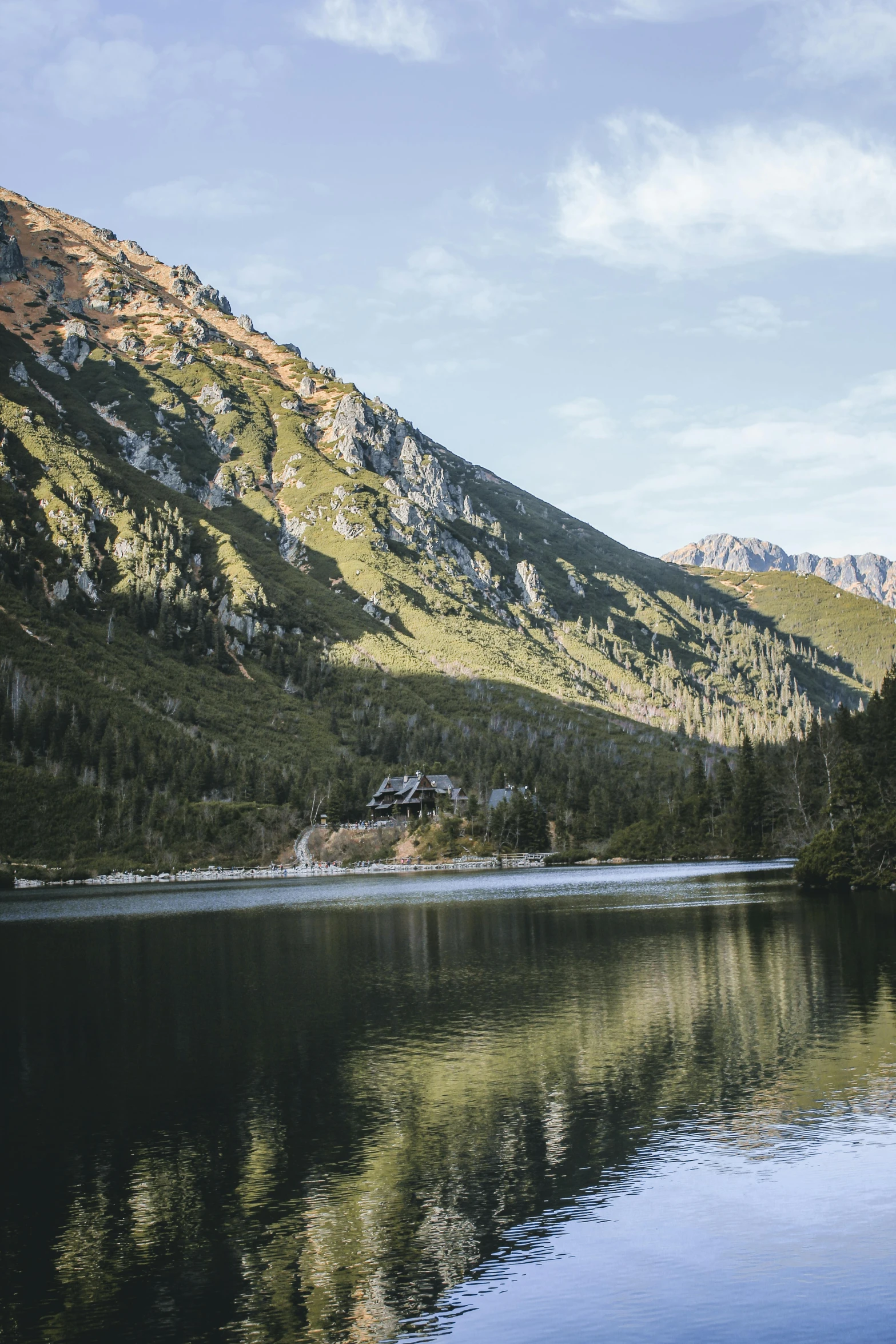 a body of water with mountains in the background, poland, cabin, multiple stories, mountainous setting