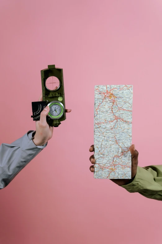 two people holding a map and a compass, an album cover, inspired by Wes Anderson, trending on unsplash, regionalism, pink and green, camouflaged gear, clemens ascher, binoculars