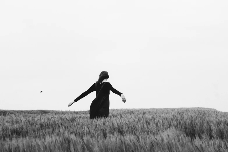 a black and white photo of a woman in a field, by Emma Andijewska, unsplash, conceptual art, saatchi art, minimalist art, of letting go, woman in black robes