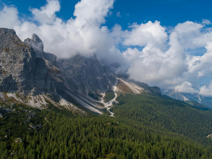 a view of the mountains from the top of a mountain, by Sebastian Spreng, pexels contest winner, lago di sorapis, aerial footage, clouds in the background, above a forest