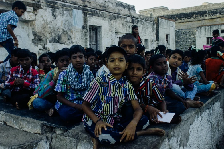 a group of children sitting on top of a cement wall, pexels contest winner, bengal school of art, audience in the background, promo image, full body image, thumbnail