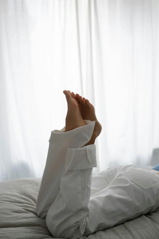 a person laying on a bed with their feet up, wearing a white shirt, up to the elbow, early morning, very comfy]
