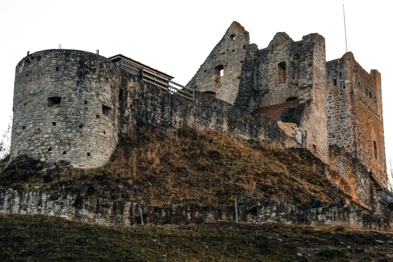 a large castle sitting on top of a hill, an album cover, by Kristian Zahrtmann, pexels contest winner, renaissance, old stone wall, exterior view, rustic, collapsed brutalist architecture