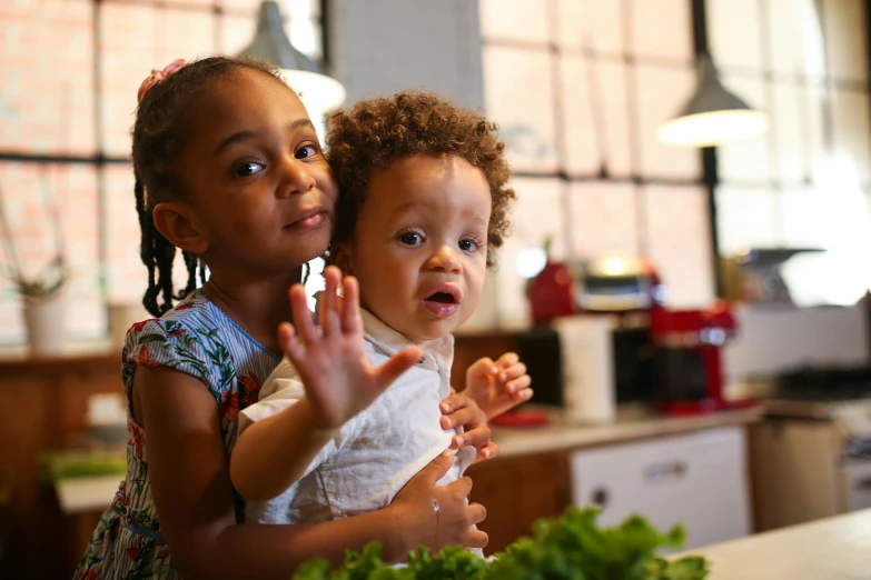 two little girls standing next to each other in a kitchen, pexels contest winner, mixed race, thumbnail, waving, younger brother vibes