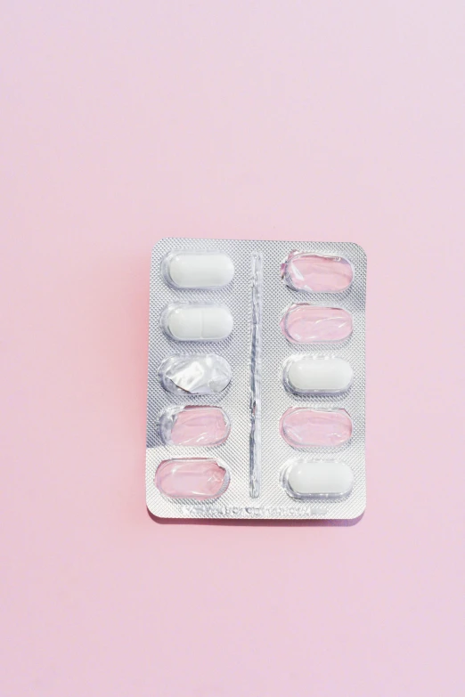 pills in a blister pack on a pink background, an album cover, inspired by Hedi Xandt, trending on pexels, plasticien, translucent white skin, icey, back facing, silver lining