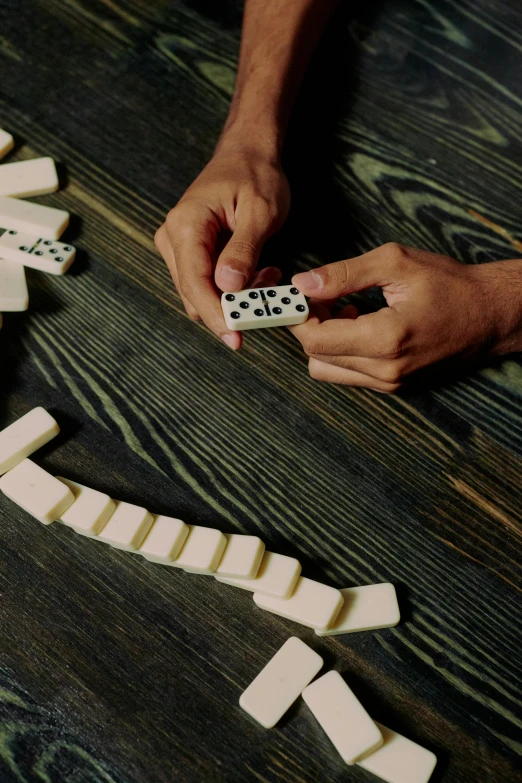 a man playing domino game on a wooden table, by Greg Rutkowski, unsplash, process art, promo image, multiple stories, bone to bone, 256435456k film