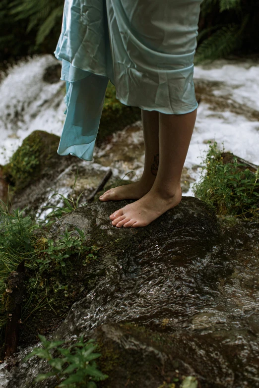 a person standing on a rock next to a stream, by Elsa Bleda, exposed toes, full frame image, feet art, slide show