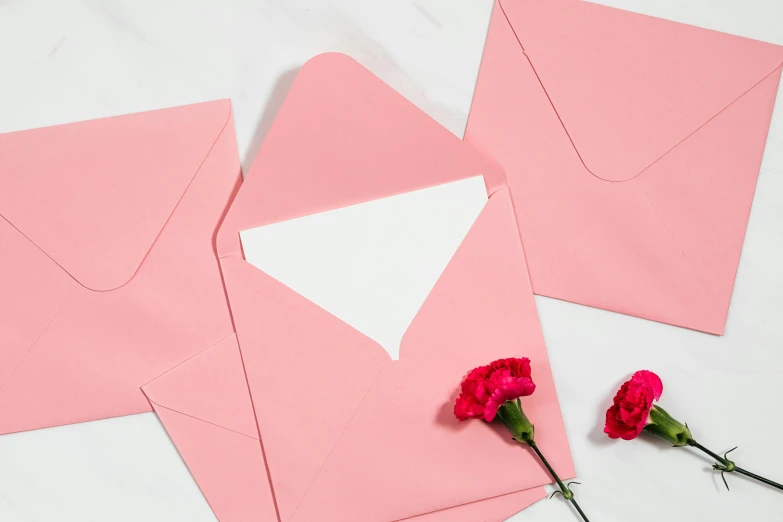 a couple of pink envelopes sitting on top of a table, flowers around, thumbnail, middle of the page, decoration