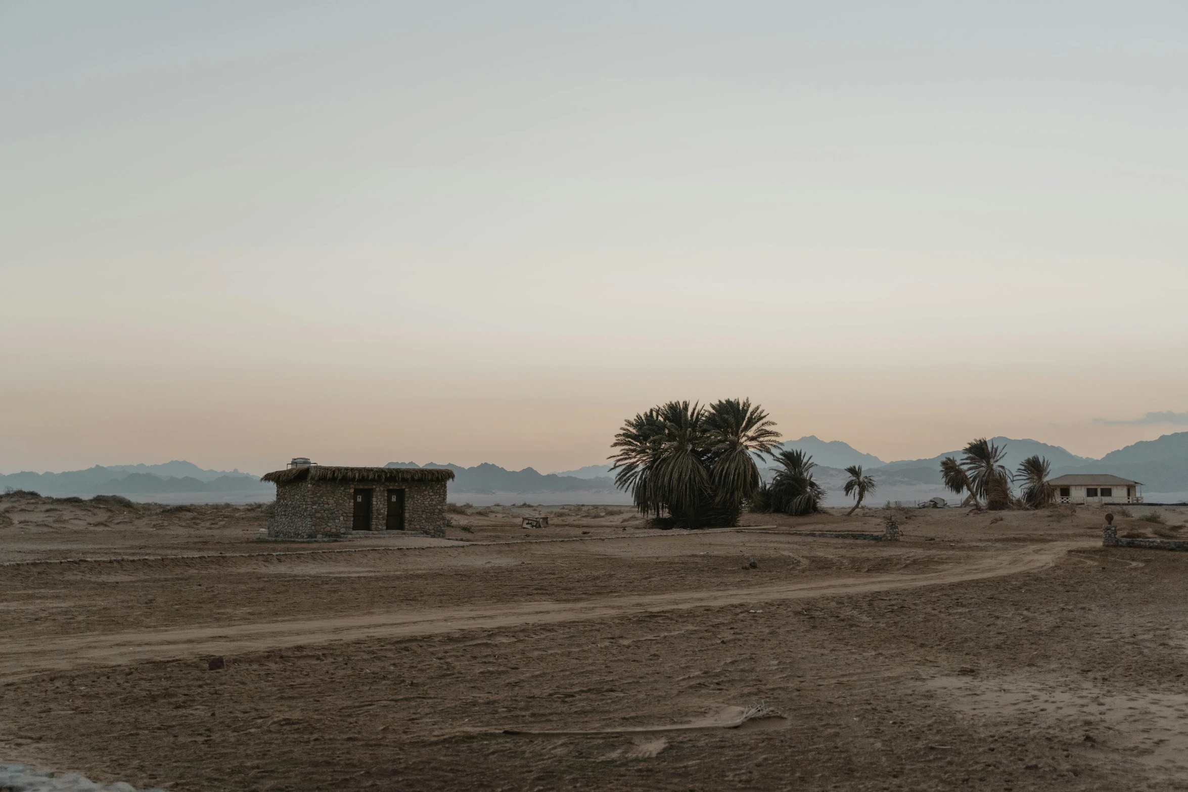 a dirt road in the middle of a desert, by Tobias Stimmer, les nabis, makeshift houses, late evening, background image, dried palmtrees