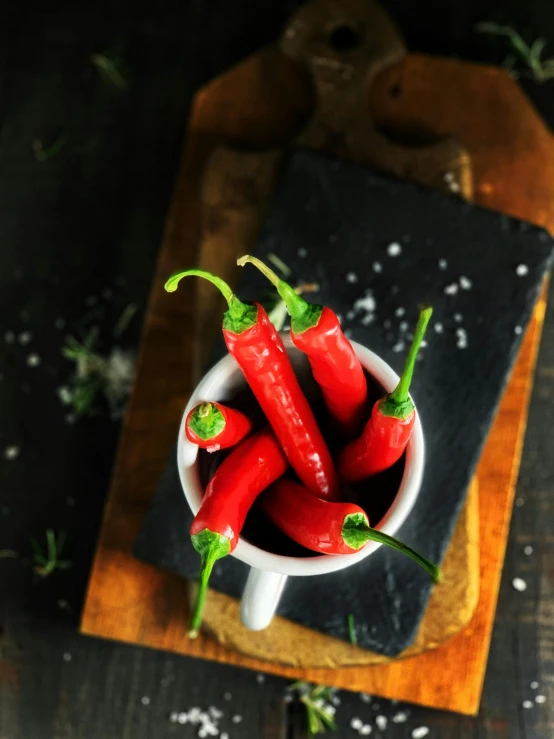 a bowl filled with red hot peppers sitting on top of a cutting board, inspired by Jan Kupecký, trending on pexels, thumbnail, product image, multiple stories, instagram picture