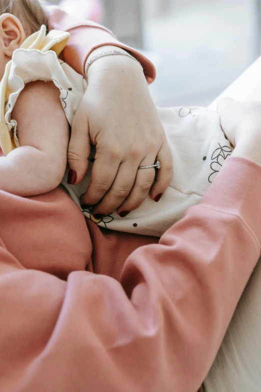 a woman holding a baby in her arms, pexels, touching her clothes, partially cupping her hands, digital image, resting