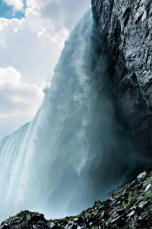 a man standing in front of a waterfall, an album cover, by Daniel Seghers, pexels contest winner, extreme closeup, niagara falls, extreme panoramic, subreddit / r / whale