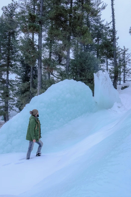 a man standing on top of a snow covered slope, inspired by Einar Hakonarson, land art, mountains made out of icebergs, spruce trees on the sides, taylor swift made of purple ice, looking sideway