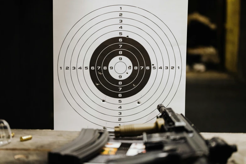 a gun sitting on top of a table next to a target, in front of a round