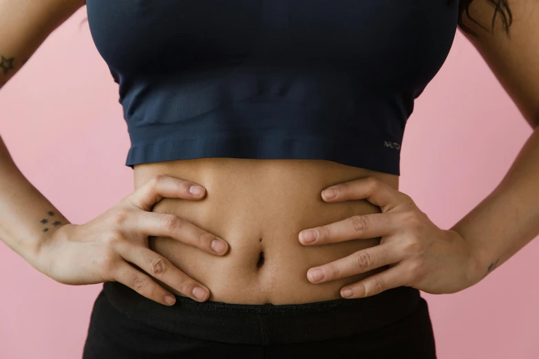 a woman with her hands on her stomach, trending on pexels, manuka, face and body clearly visible, pink, belly