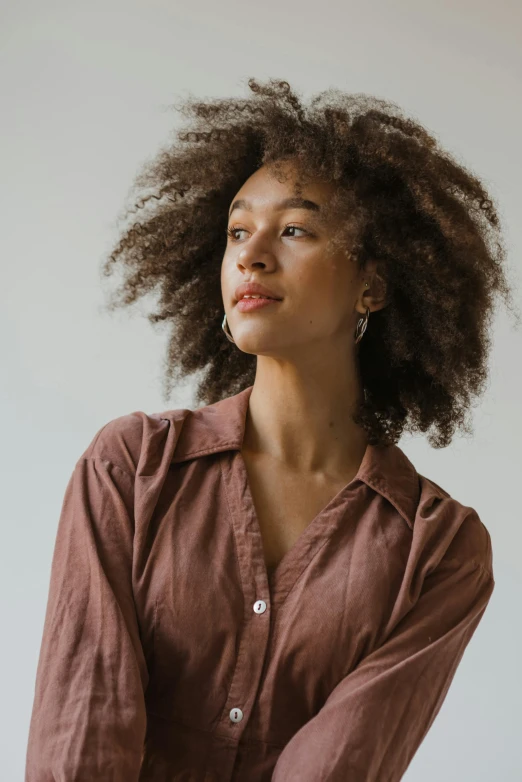 a woman standing in front of a white wall, a character portrait, inspired by Afewerk Tekle, trending on unsplash, renaissance, brown shirt, hair : long brown, collared shirt, ashteroth