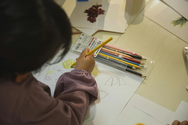 a little girl is drawing with colored pencils, inspired by Elsa Beskow, pexels contest winner, do hoang tuong artwork, in a workshop, on a yellow canva, stanley artgem lau