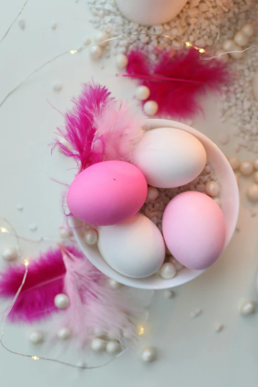 a bowl filled with eggs sitting on top of a table, pink and pink details, colored feathers, ((pink)), holiday season