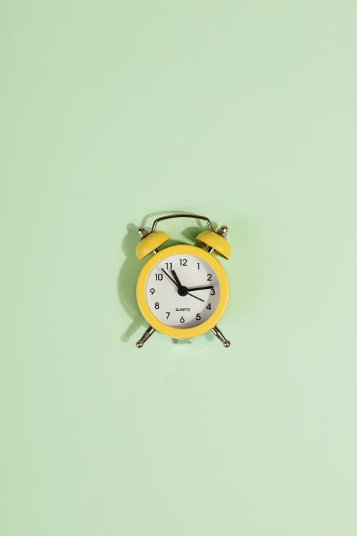 a yellow alarm clock sitting on top of a green wall, jen atkin, tinnitus, mint, mix