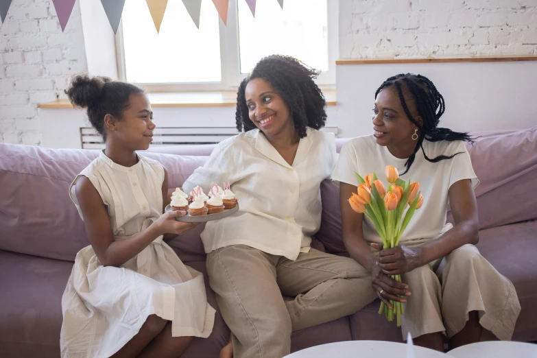 three women sitting on a couch eating cupcakes, a portrait, pexels, flowers, african american girl, motherly, white