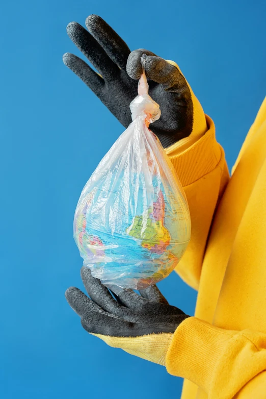 a person in a yellow jacket holding a bag of garbage, an illustration of, by Dan Content, plasticien, large globe, multi - coloured, ldpe, detail shot