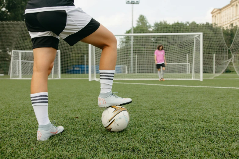 a person kicking a soccer ball on a field, looking at the ground, male and female, schools, compression