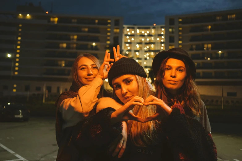 three women making a heart with their hands, an album cover, inspired by Elsa Bleda, pexels contest winner, graffiti, rooftop party, college girls, night time low light, heart shaped face