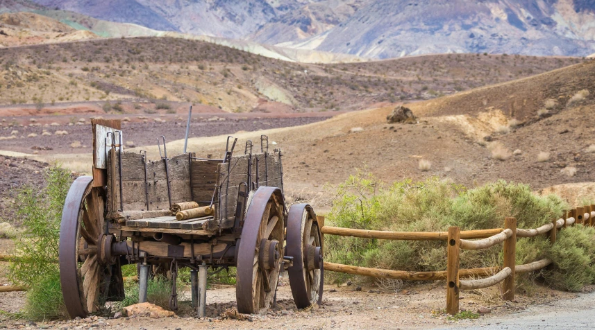 an old wagon is parked on the side of the road, by Julia Pishtar, trending on unsplash, desert valley of bones, entrance to 1900's mine, benches, andes