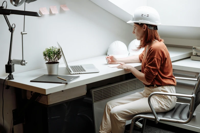 a woman sitting at a desk with a laptop, hard hat, minimalistic aesthetics, worksafe. instagram photo, profile image