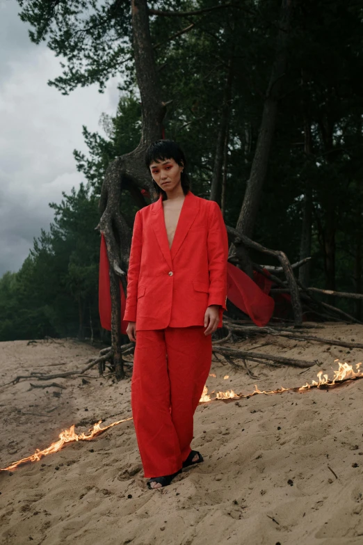 a woman in a red suit standing on a beach, an album cover, by Attila Meszlenyi, woods on fire, official store photo, gongbi, artem chebokha