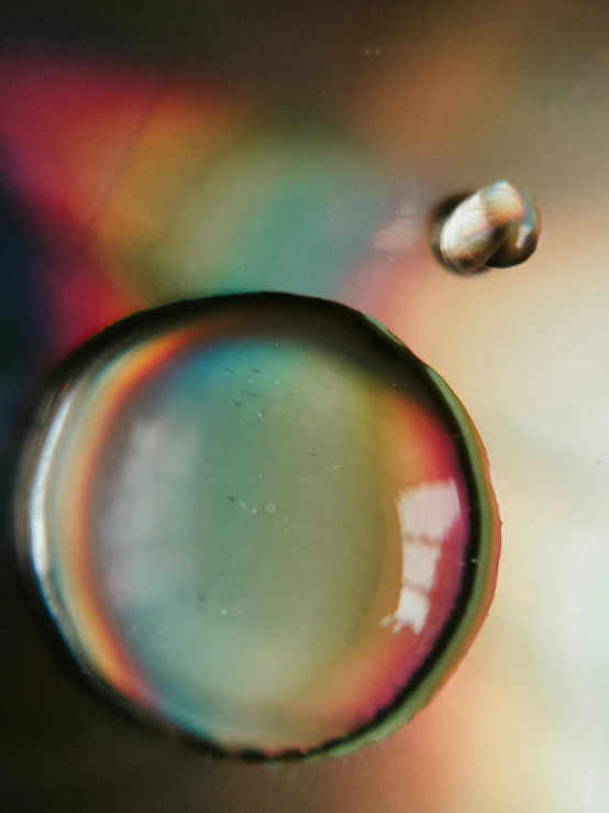 a close up of a water drop with a rainbow in the background, a macro photograph, unsplash, holography, color grain 3 5 mm, 4k)