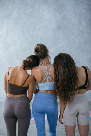 a group of three women standing next to each other, trending on pexels, detailed sports bra, back of the hair, curated collection, indoor picture