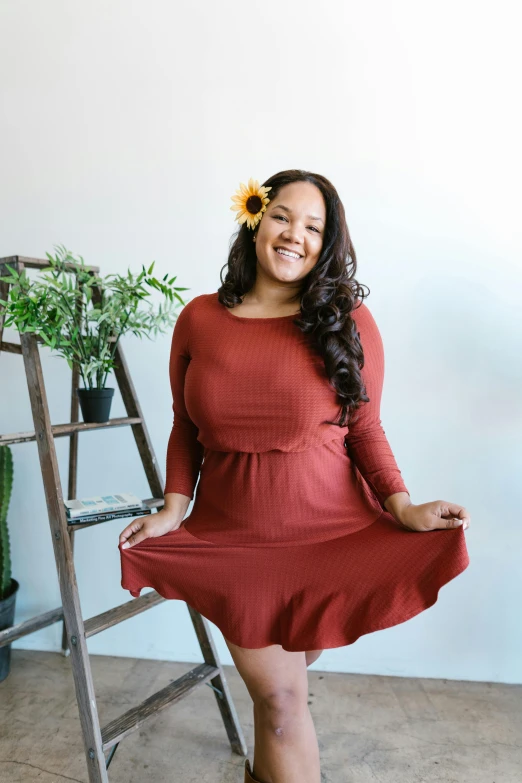 a woman in a red dress standing next to a ladder, pexels contest winner, sitting on a mocha-colored table, organic dress, curvy and bow, designed for cozy aesthetics!