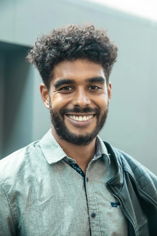 a man with a beard smiles at the camera, by Jacob Toorenvliet, dark short curly hair smiling, jayison devadas, young male, professional profile photo