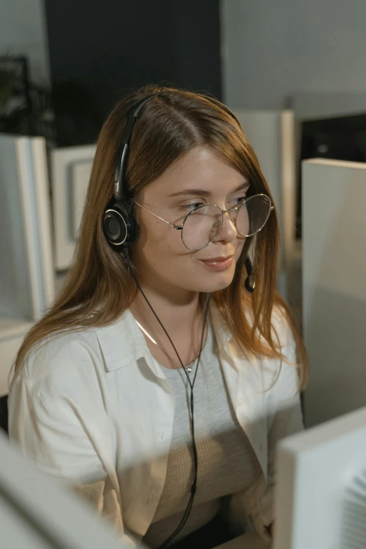 a woman wearing headphones sitting in front of a computer, rounded eyeglasses, calmly conversing 8k, glasses |