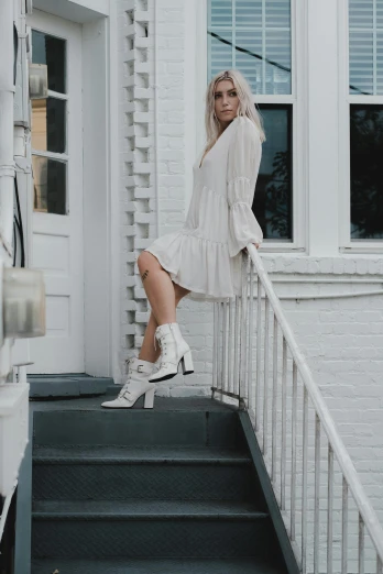 a woman standing on the steps of a house, a statue, by Sara Saftleven, pexels contest winner, neo-romanticism, white dress!! of silver hair, wearing boots, scandinavian style, fashion outfit