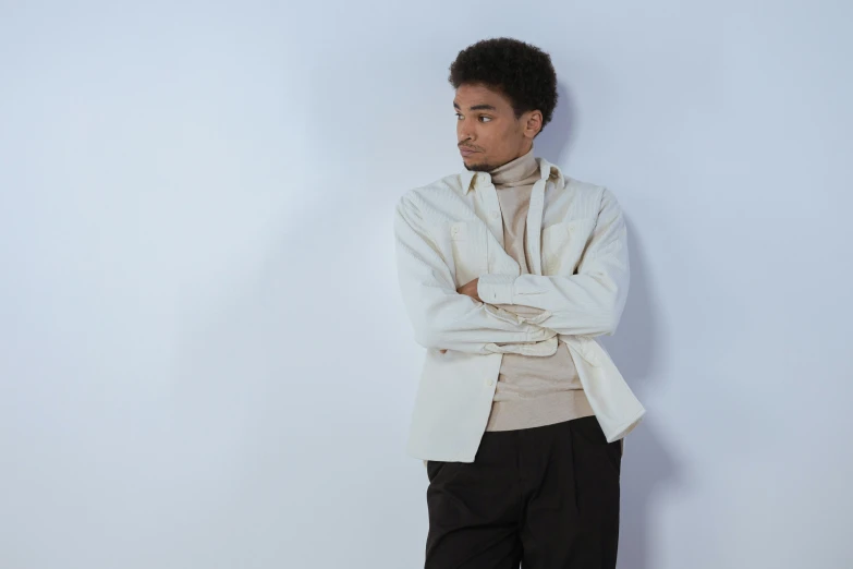 a man standing in front of a white wall, an album cover, inspired by Theo Constanté, wear's beige shirt, wearing a turtleneck and jacket, ignant, with a lab coat