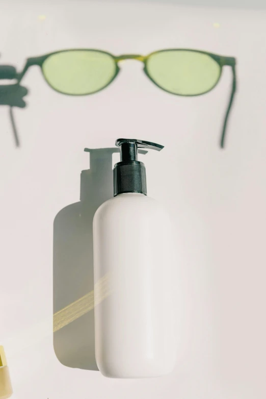 a bottle of lotion next to a pair of sunglasses, trending on pexels, photorealism, upper body close - up, with a long white, product view, looking from shoulder