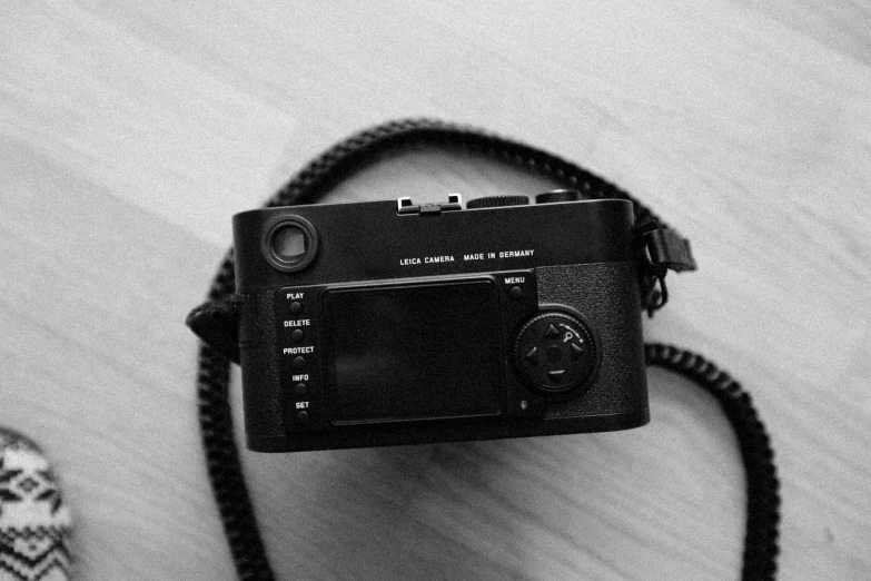 a camera sitting on top of a wooden table, a black and white photo, by Adam Rex, minimalism, leica m9, back camera, all black matte product, ! low contrast!