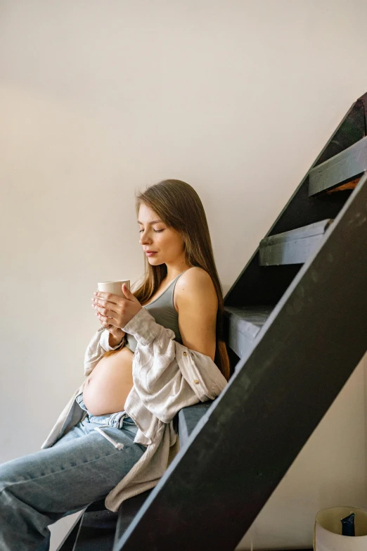 a pregnant woman is sitting on the stairs, trending on pexels, drink more coffee, gen z, grey, wētā fx