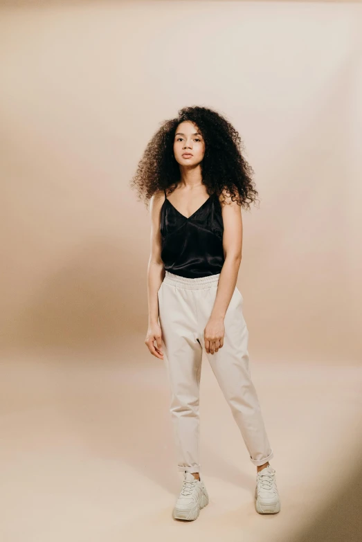 a woman in a black top and white pants, by Cosmo Alexander, trending on pexels, renaissance, mixed race, neutral background, wearing : tanktop, tailored clothing