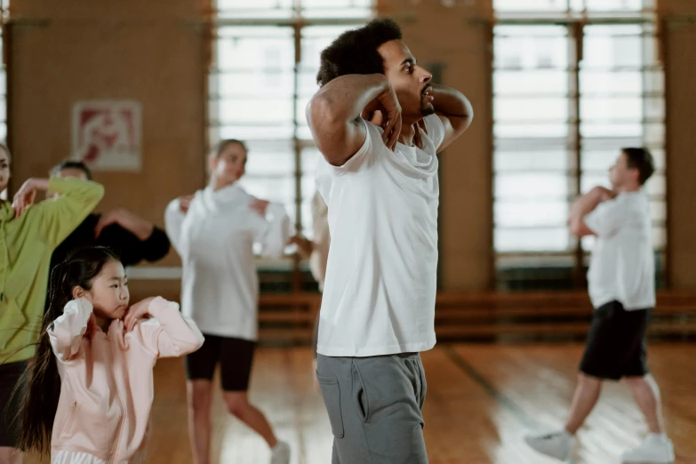 a group of people standing on top of a wooden floor, pexels contest winner, arabesque, man in adidas tracksuit, families playing, manuka, choreographed