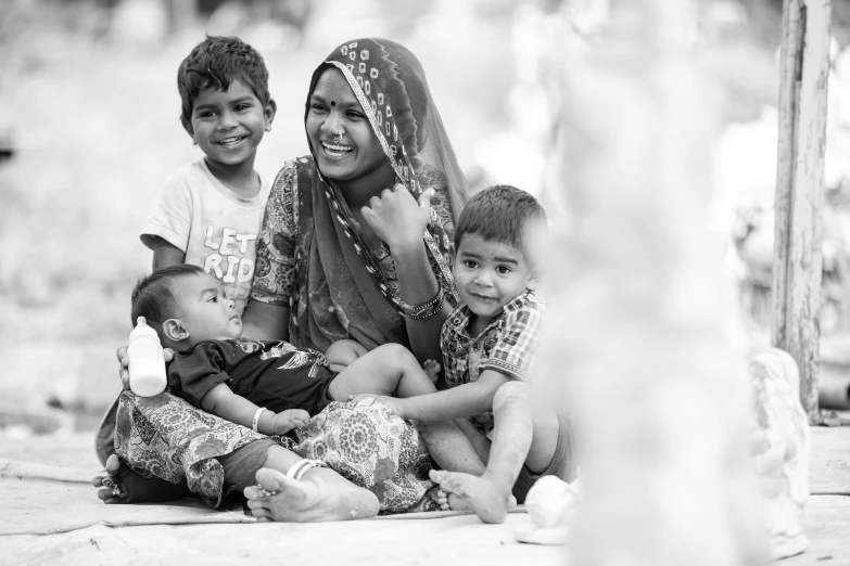 a woman sitting on the ground with two children, a black and white photo, pexels contest winner, hurufiyya, proud smile, bangladesh, husband wife and son, islamic