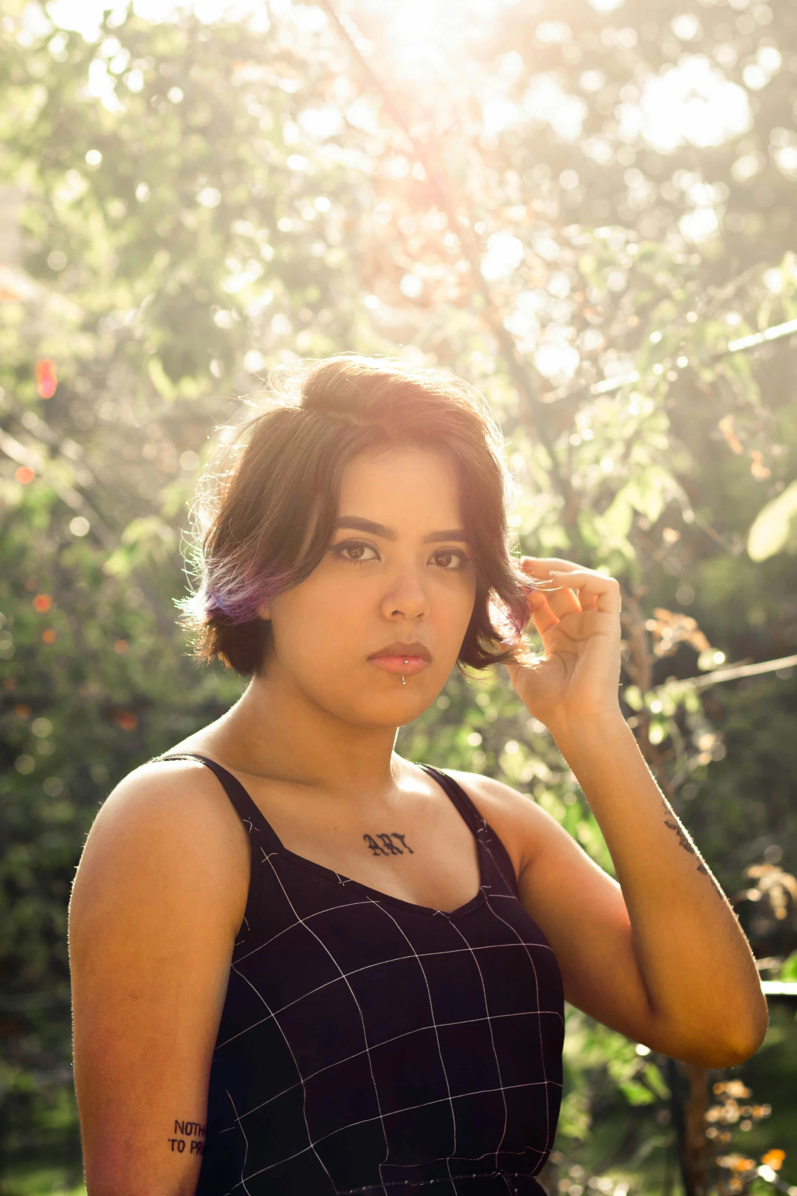 a woman in a black dress posing for a picture, inspired by Elsa Bleda, chin-length purple hair, alanis guillen, sunlight beaming down, with short hair