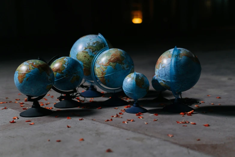 a group of small globes sitting on top of a floor, earth seen on the dark sky, for hire 3d artist, large props, blue marble