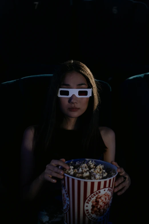 a woman wearing 3d glasses holding a bucket of popcorn, a hologram, inspired by Gottfried Helnwein, pexels, an asian woman, [ theatrical ], night vision, avatar image