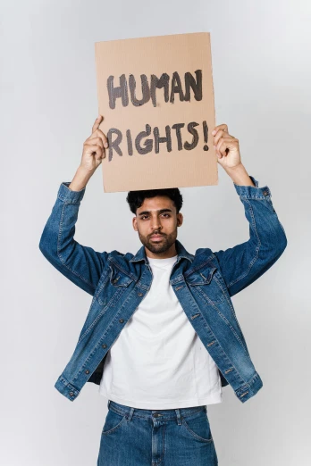 a man holding a sign that says human rights, an album cover, trending on pexels, renaissance, indian, handsome man, light skin, human form