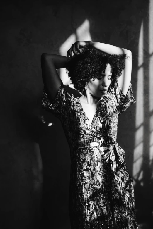 a black and white photo of a woman in a dress, pexels contest winner, curly afro, in a silk robe, her hand is on her waist, vibrant light