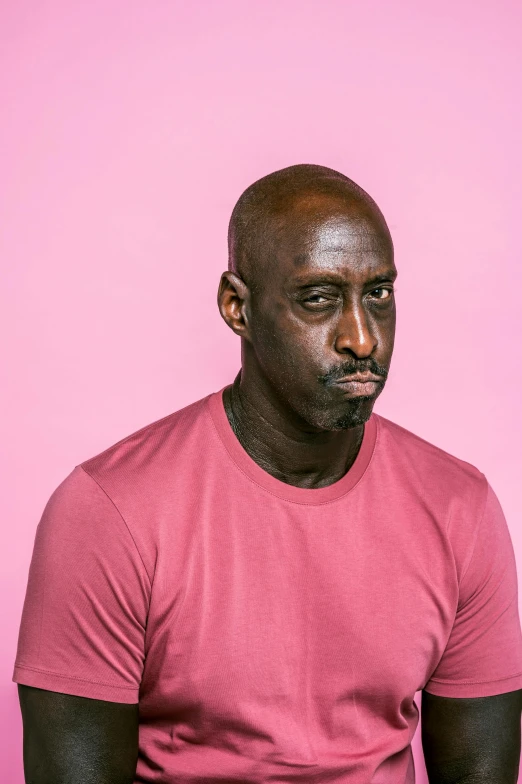 a man sitting in front of a pink wall, an album cover, by David Begbie, pexels contest winner, les nabis, lance reddick, mkbhd as iron man, headshot profile picture, pouty